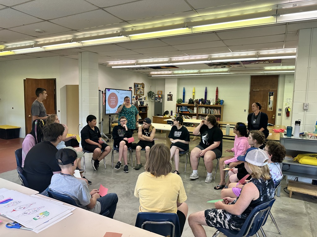 Camp participants are seated in a circle during an ASL activity. 
