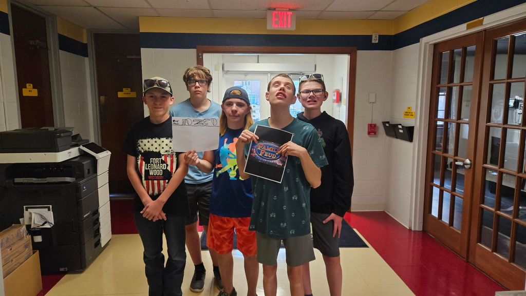 A group of camp participants stand side by side holding up a "Family Feud" paper. 