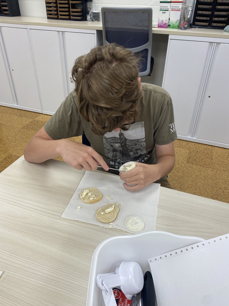 A male camp participant looks down as he concentrates on putting butter on his piece of bread. 