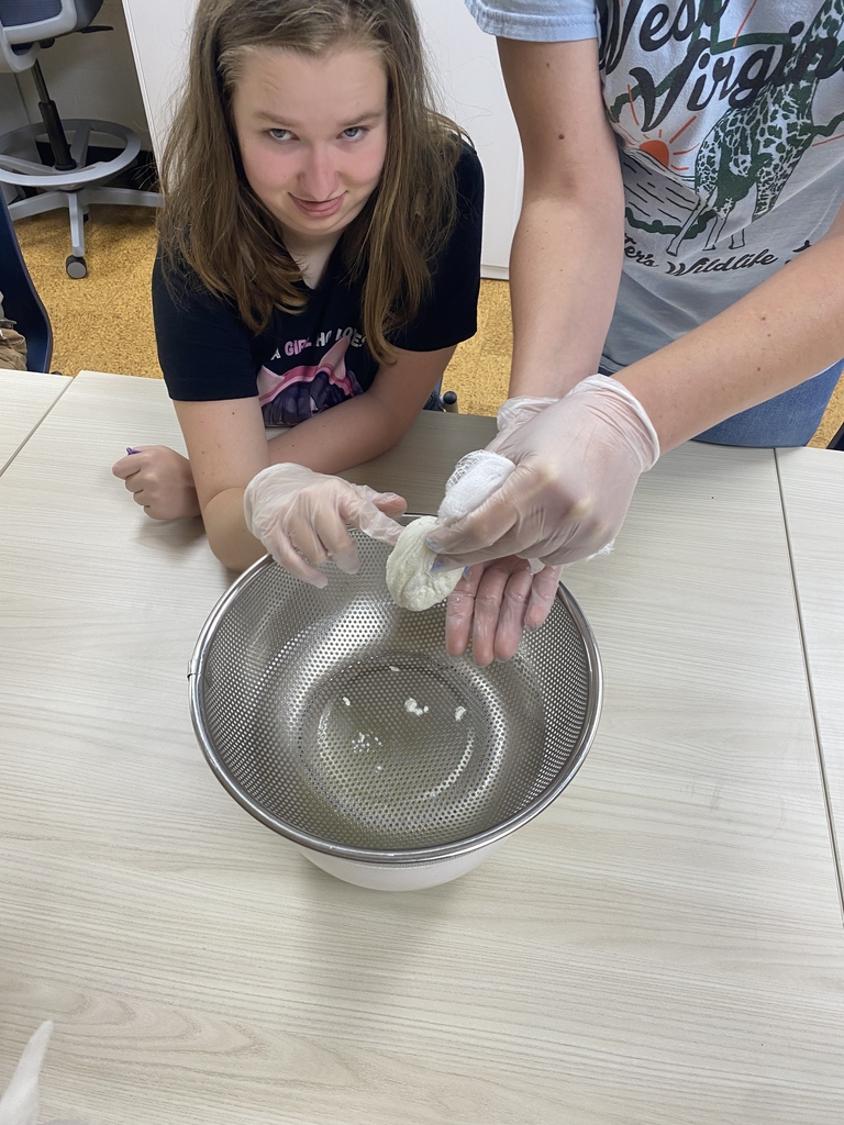 A female camp participant looks up with a silly face as she touches freshly made dough.
