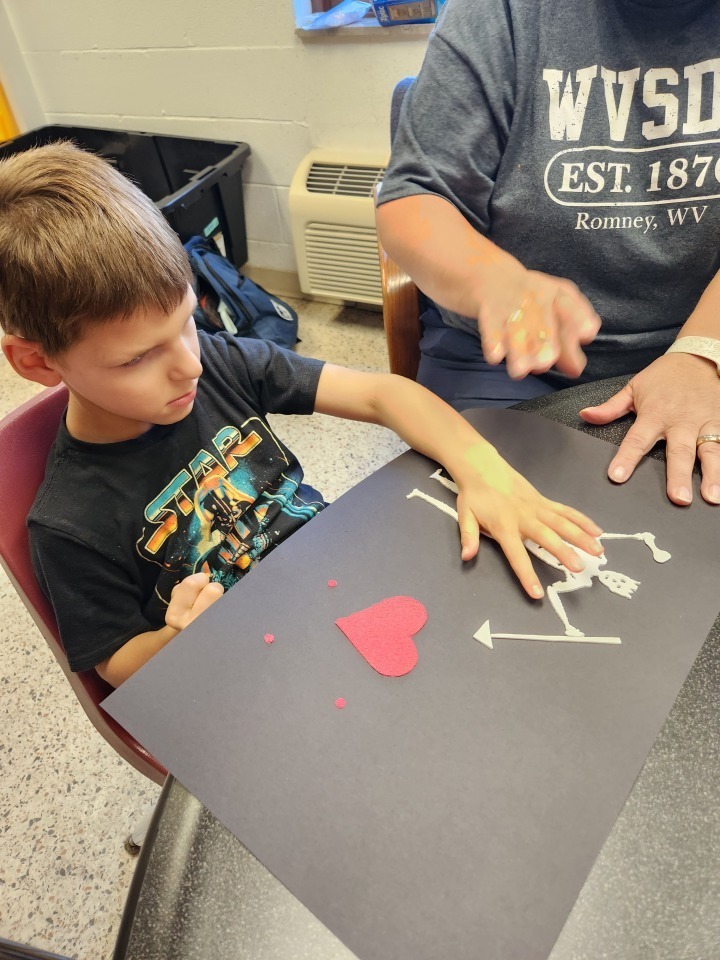 A male camp participant touches a white tactile figure. 