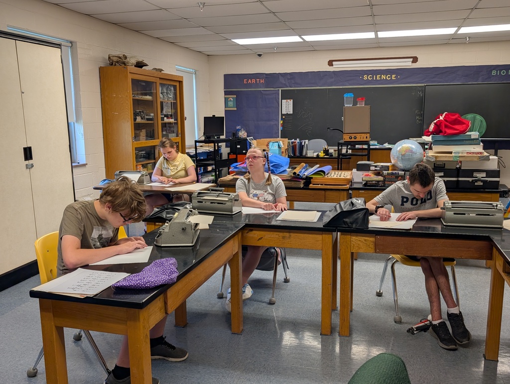 A group of camp participants seated around a table concentrate on reading Braille through touch.