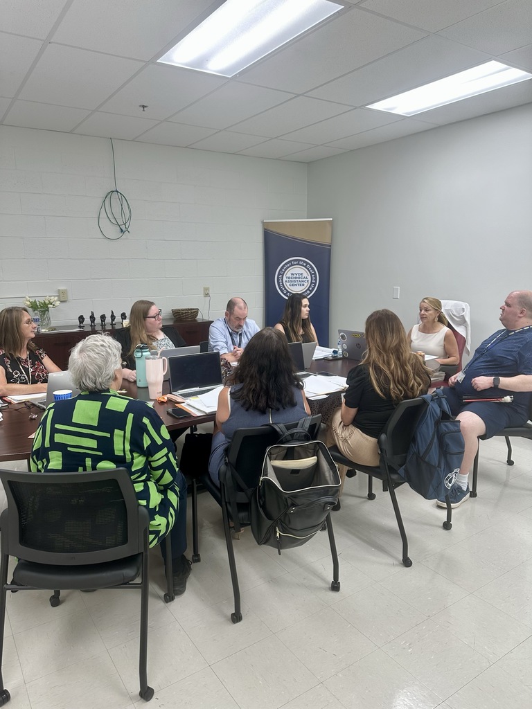 The WVSDB Outreach staff is seated around a large table discussing the plans for the upcoming school year.