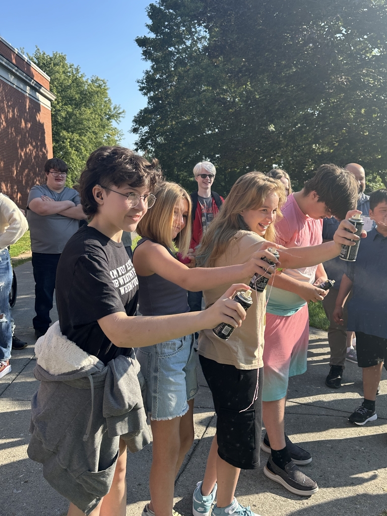 Students standing side by side as they hold cans of silly string.