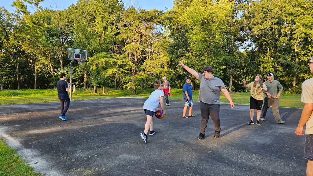 Students playing a game of basketball outdoors.