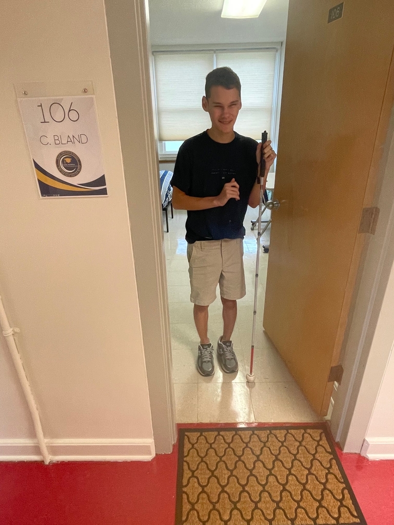 A male CAP student stands outside his dorm room for a photo.