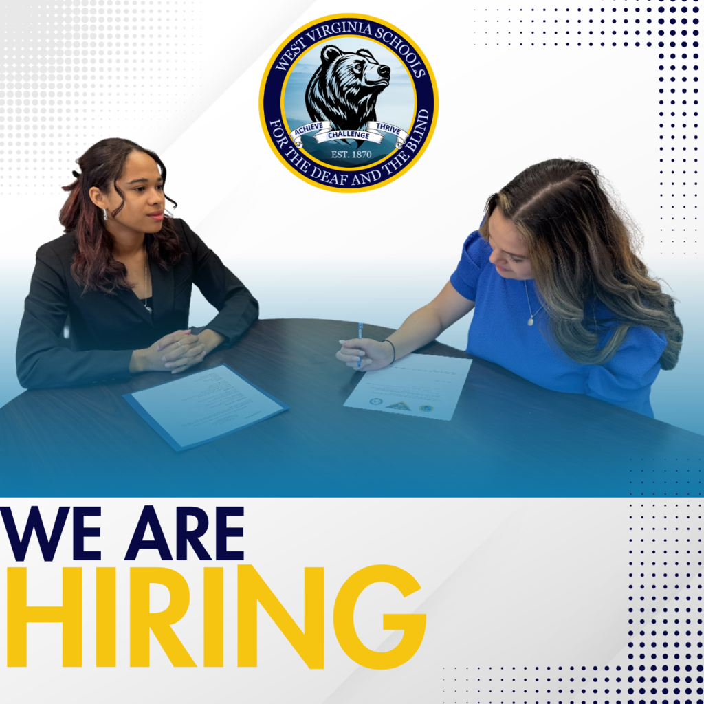 2 individuals at interview table with We Are Hiring banner