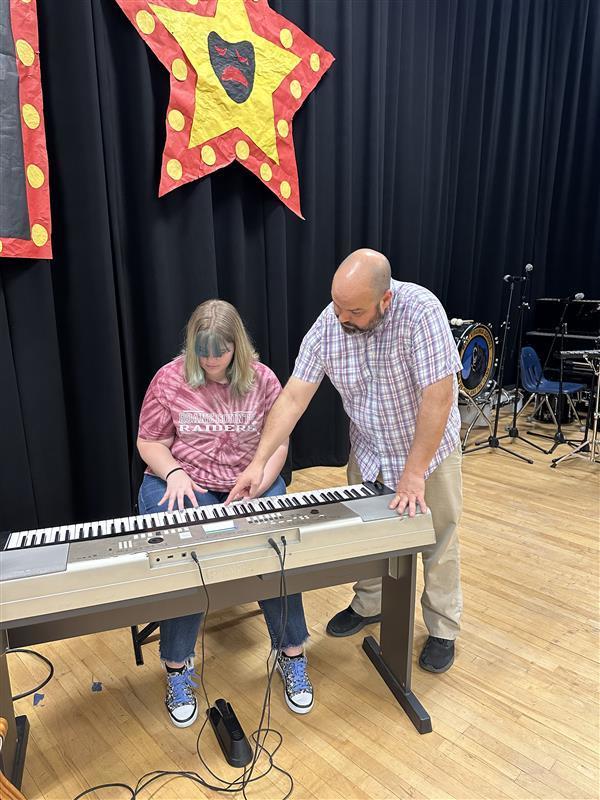 Mr. Haza - Music Instructor helps a student learn the keys on a musical keyboard.