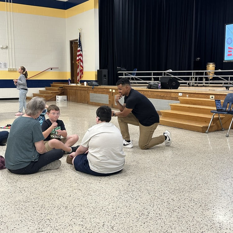 Justin Perez kneels down and observes a group of male students who are using Visual Vernacular.