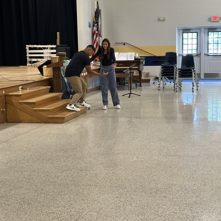 A female student stands with Justin Perez as they act out throwing an invisible ball back and forth to one another.