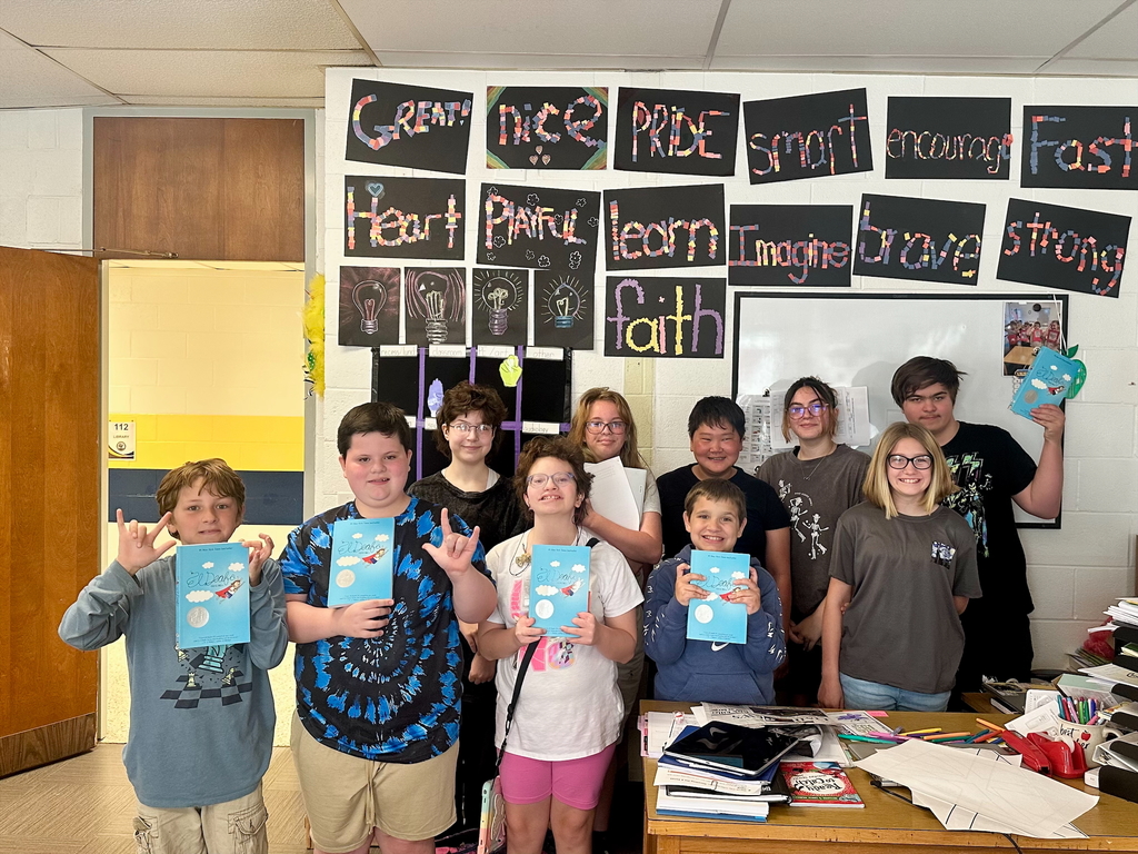 Group photo of elementary and middle school students together. The elementary students are holding up their blue "El Deafo" books.