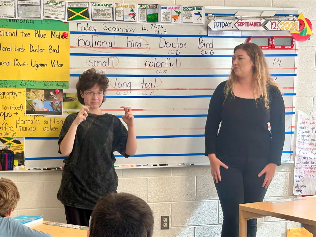 Steshka, a female student stands in front of the class as she acts out the story using ASL.