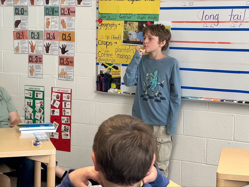 Timber, a male student stands at the front of the classroom while he signs using ASL.