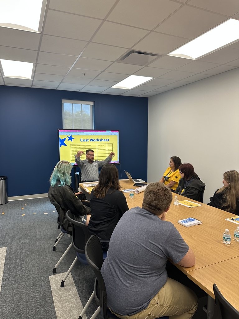 Superintendent Burch discusses mural ideas with students as they are seated at a conference table.