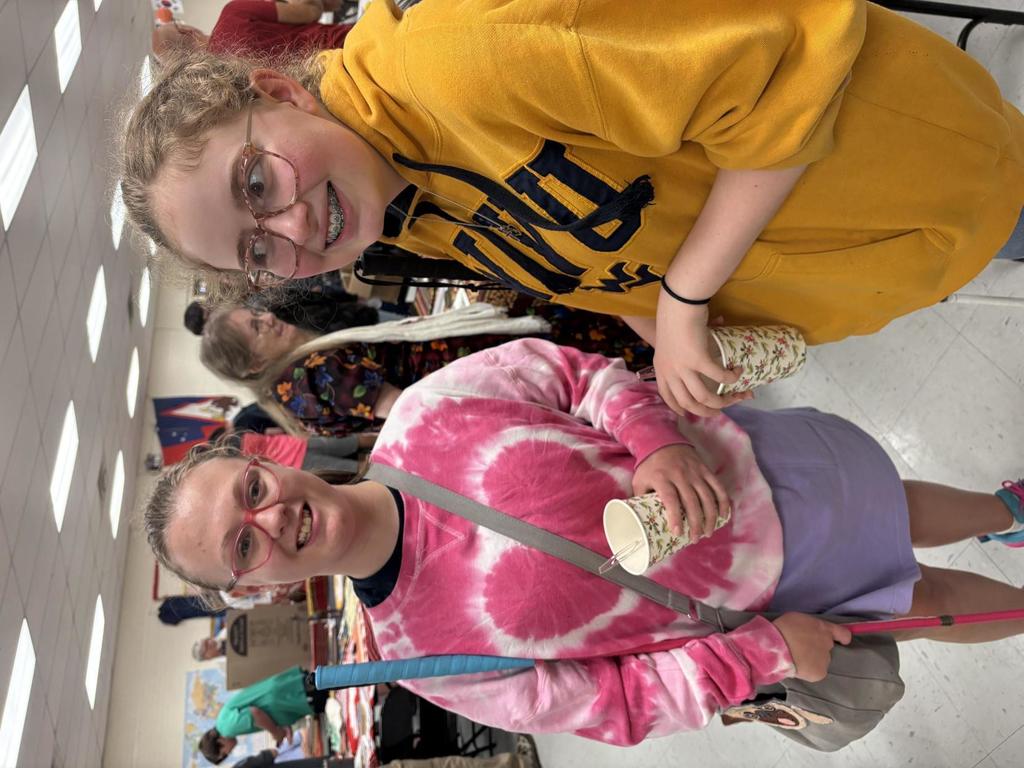 Two female students' side by side and smile for the camera.