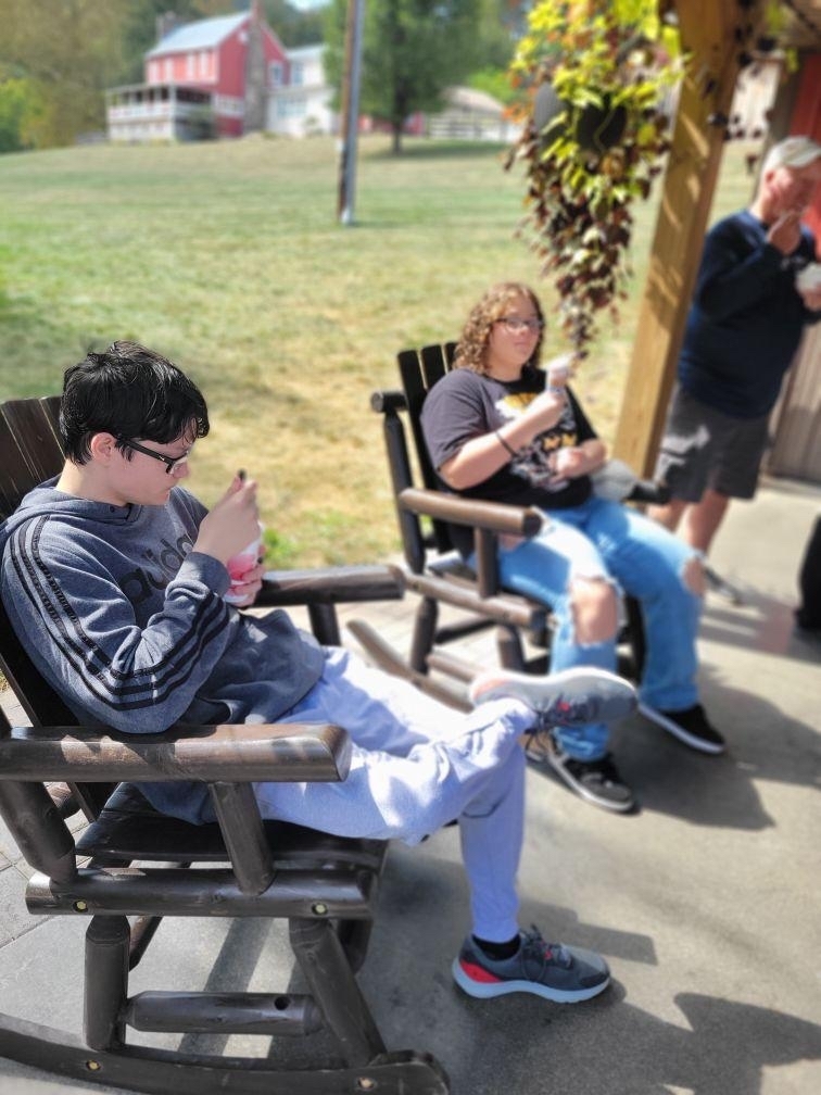 Students seated in wooden rocking chairs while they enjoy their ice cream.