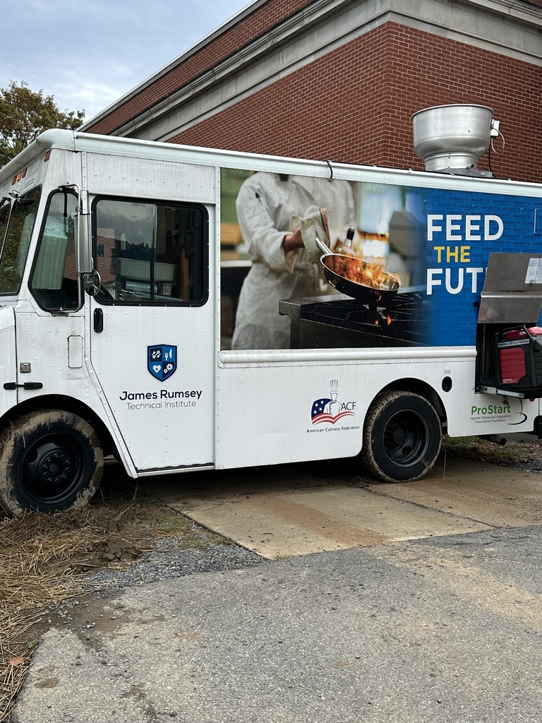A white food truck with a picture of a frying pan and a tagline that says, "Feed the Future."