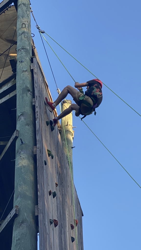 A male student climbs up a rock wall.