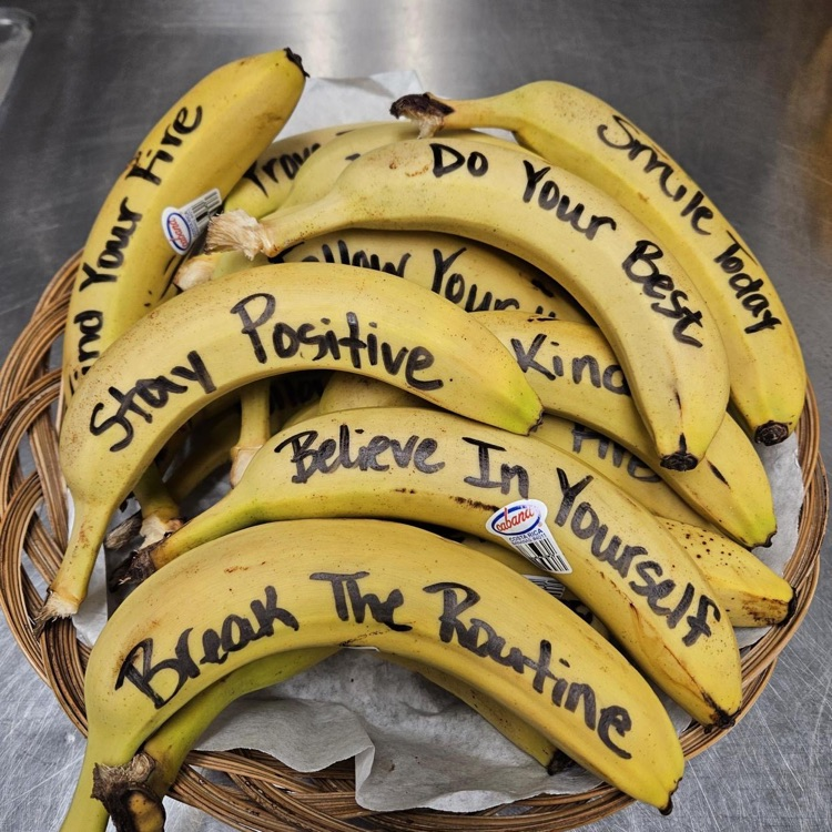 A basket full of yellow bananas with motivational quotes written on each banana.