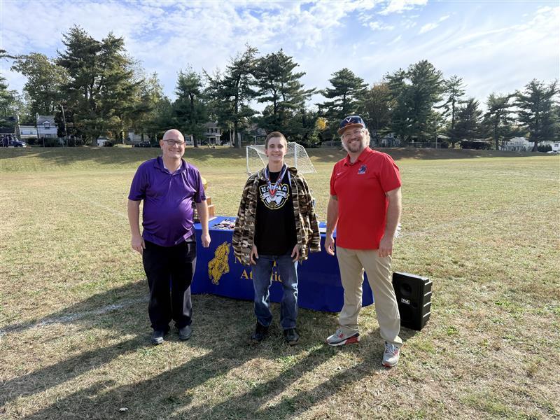 James, a male student poses with tournament officials with his All-Star award.