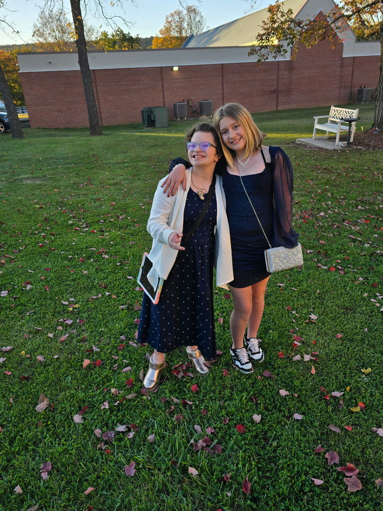 Two female students dressed in their semi-formal attire pose for a photo together.