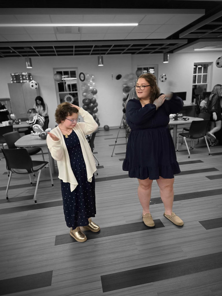 Two female students dancing side-by-side.