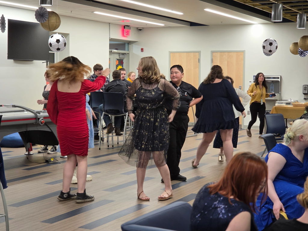 Students in a group dancing with one another.