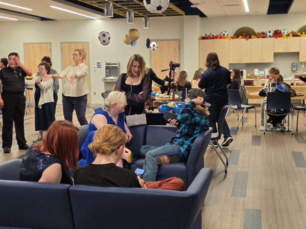 Students seated on blue-colored couches mingling with one another.