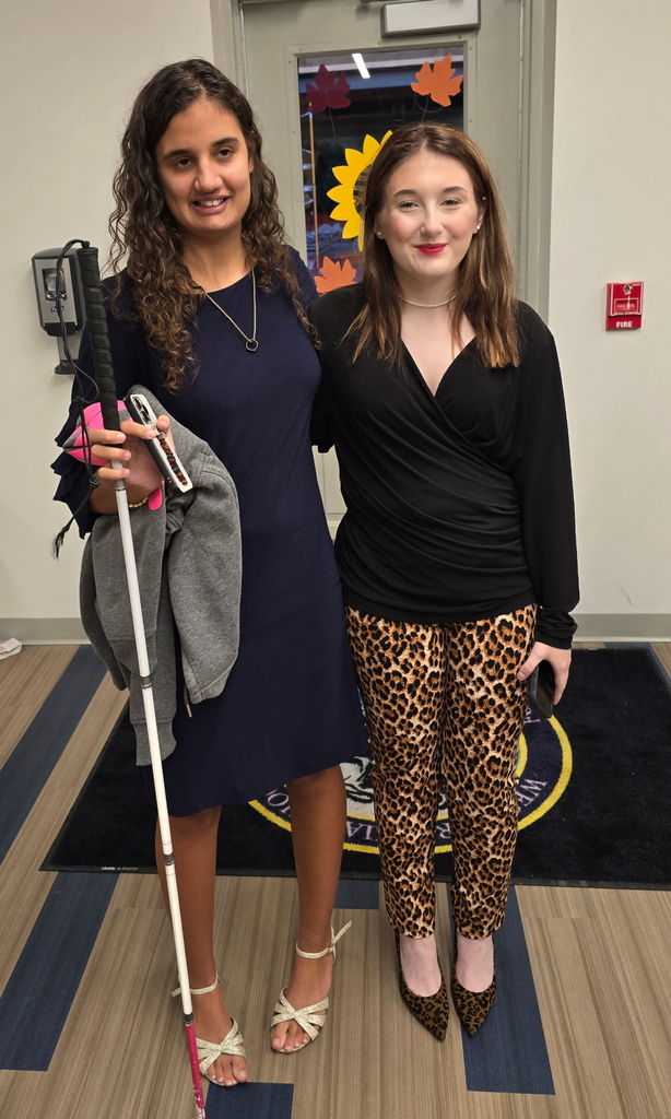 Two female students stand side-by-side and smile for the camera, dressed in their semi-formal attire.