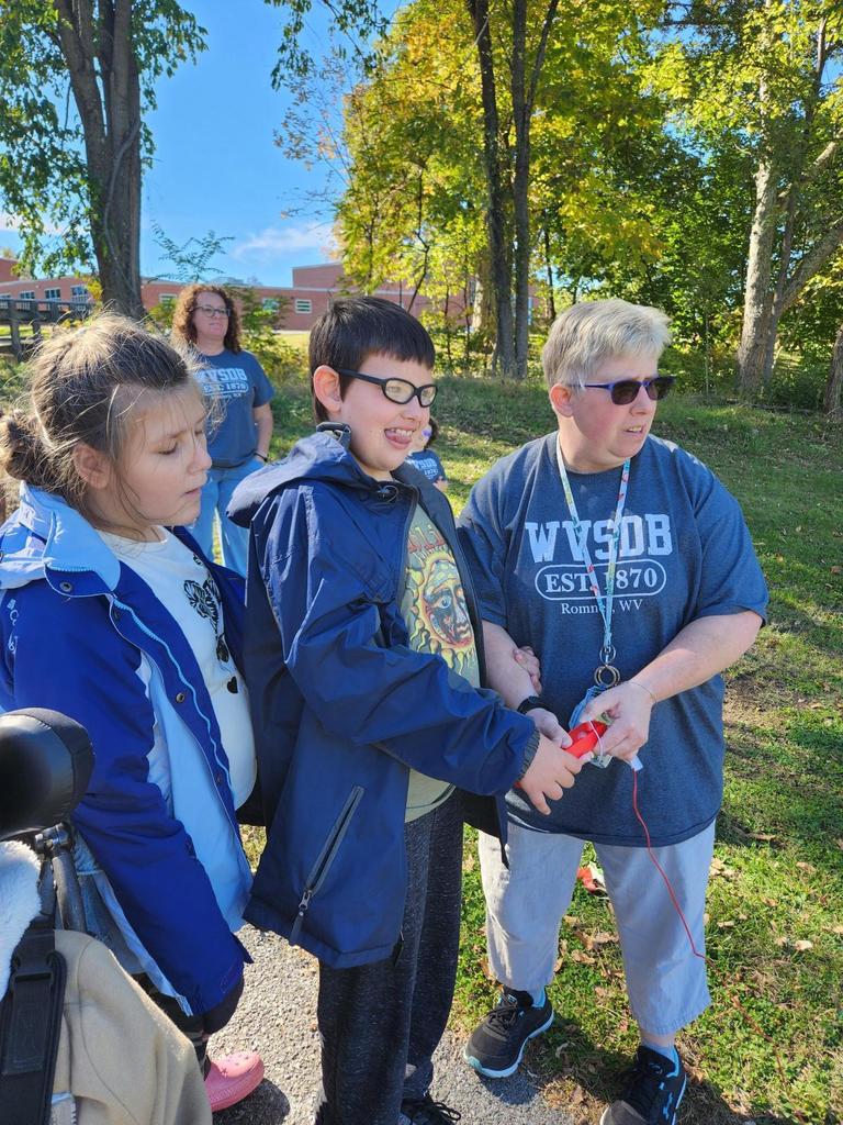 Ms. Biddle assists two students with launching their rocket using the controller.