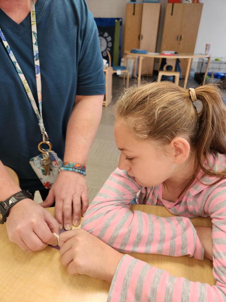 A female student looks down as she sands a part of the rocket before it is assembled.