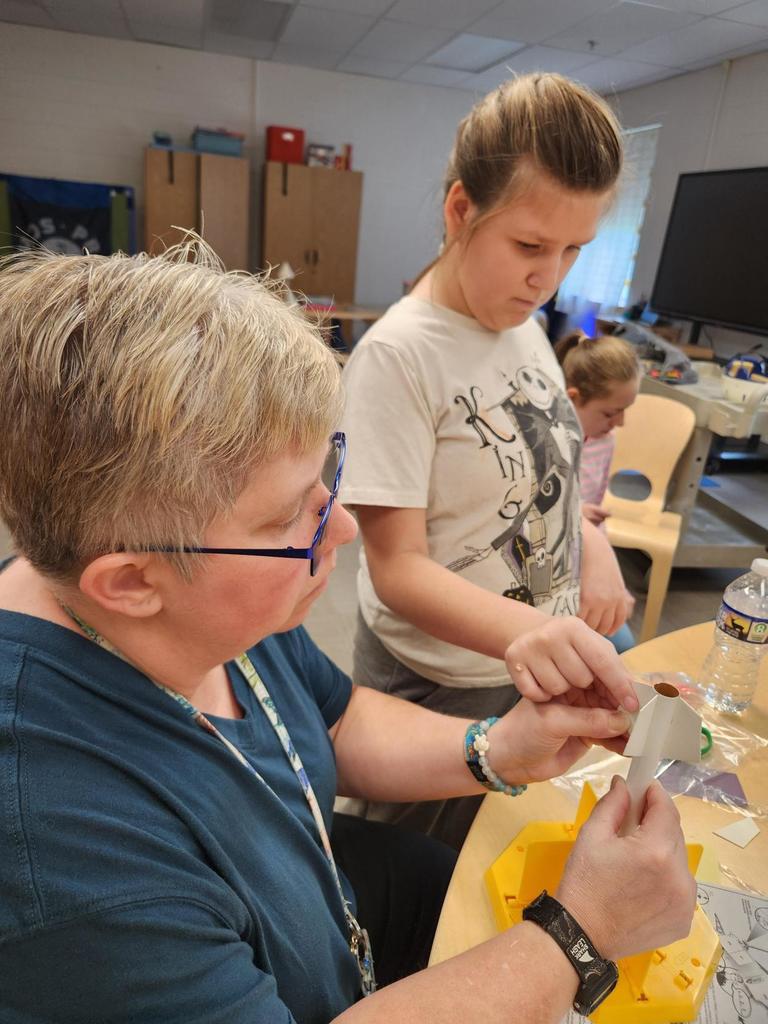 A female student assists Ms. Biddle as they put together the tail of the rocket.
