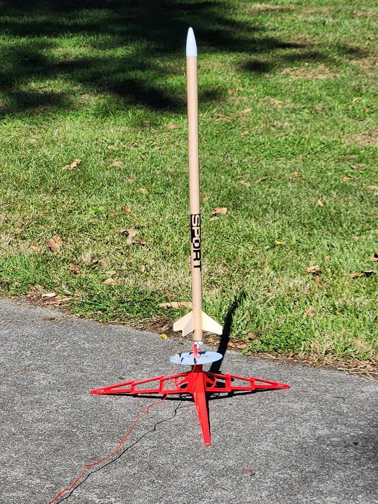 A tan-colored rocket sits on a red-colored launchpad.