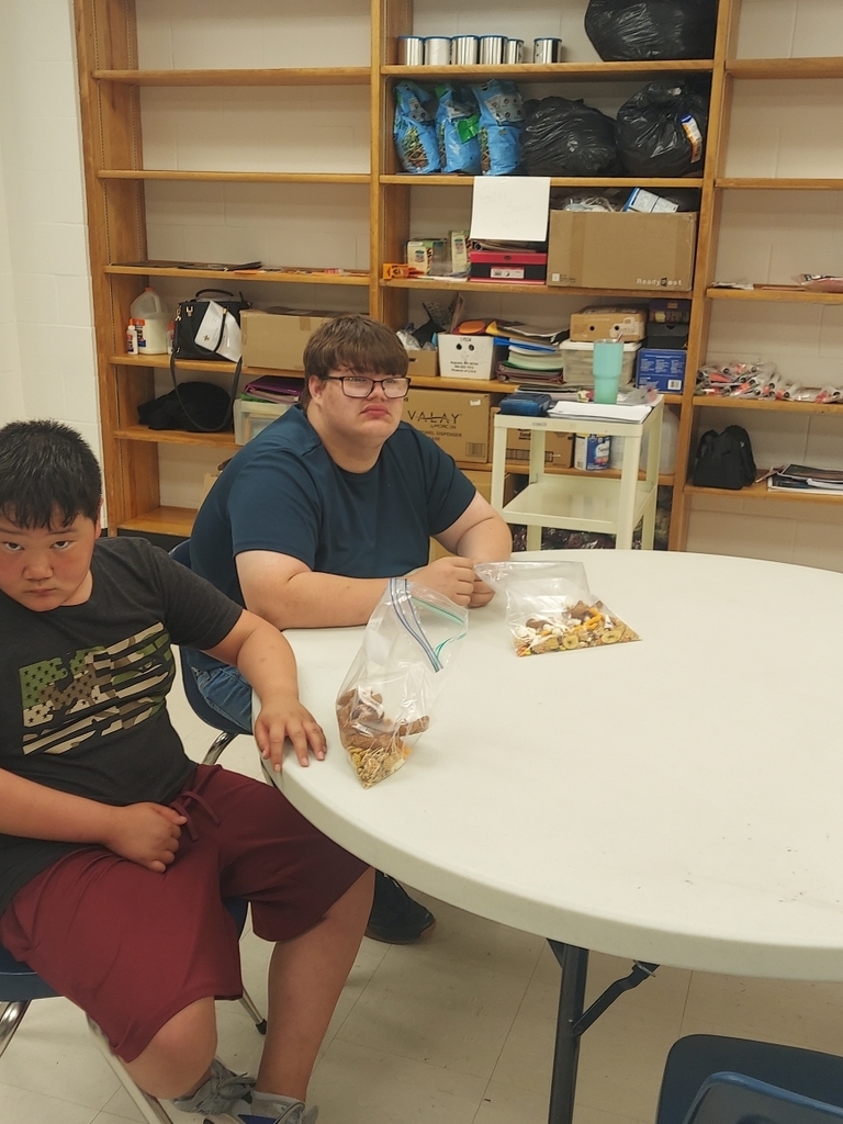 Two male students seated at a circular table with their bags of trail mix sitting in front of them.