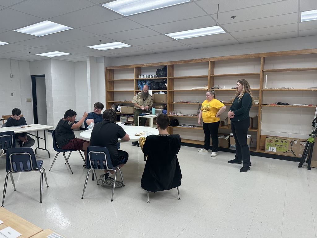 Boy Scout participants seated around a circular table as they meet with their Scout Leader.