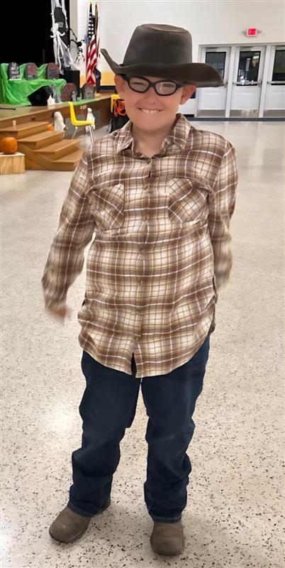 A male student dressed up as a cowboy smiles.