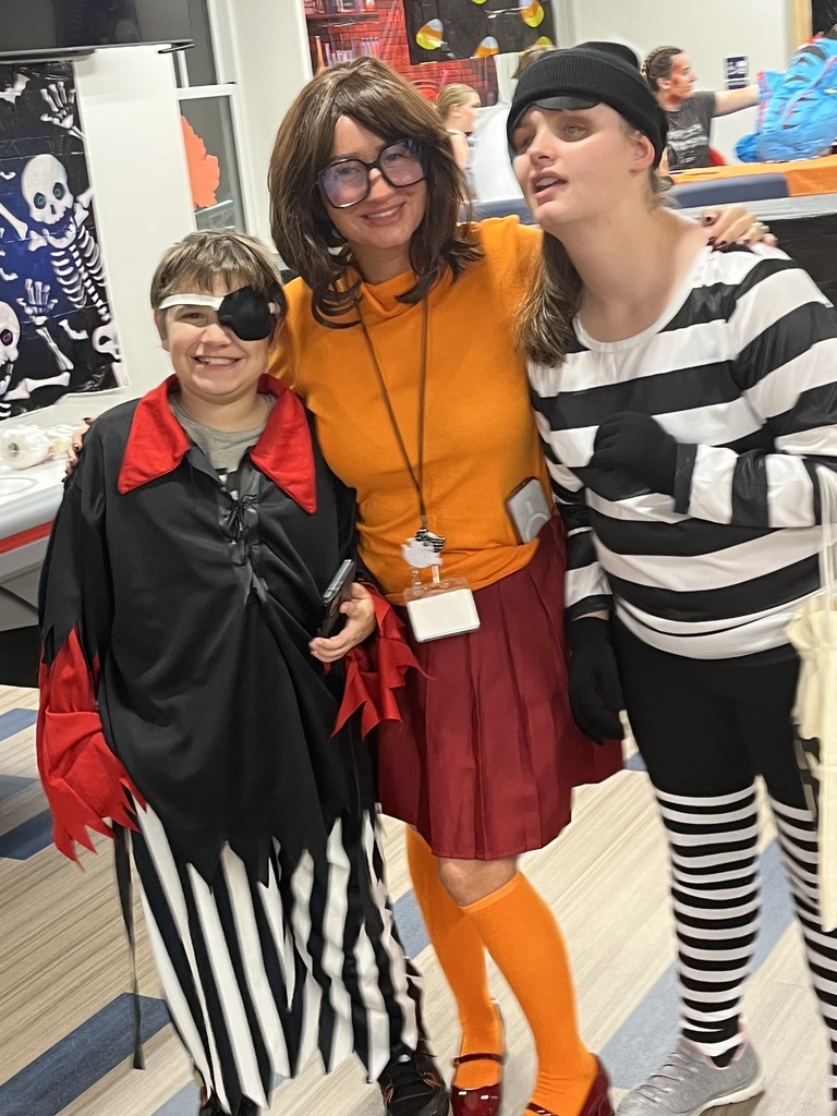 A female staff member poses with two students in their Halloween costumes.