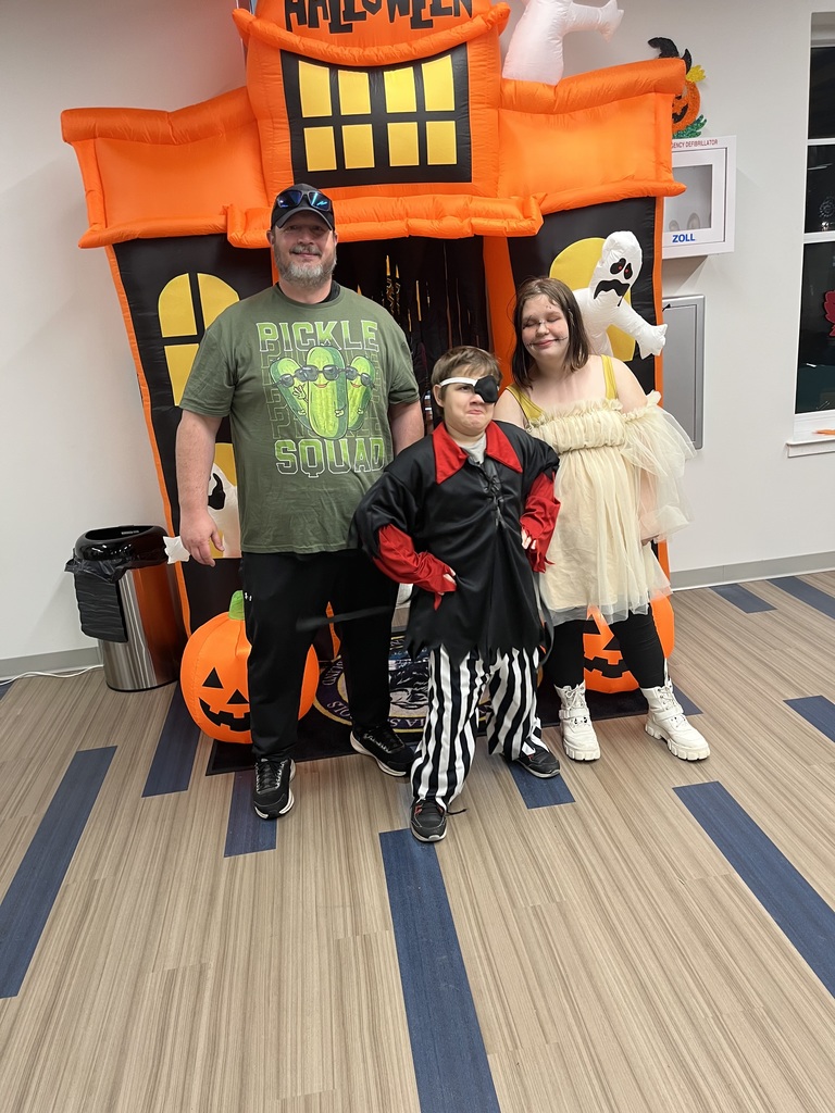 A male Residential Care Specialist (RCS) poses with two students who are dressed in their Halloween costumes.