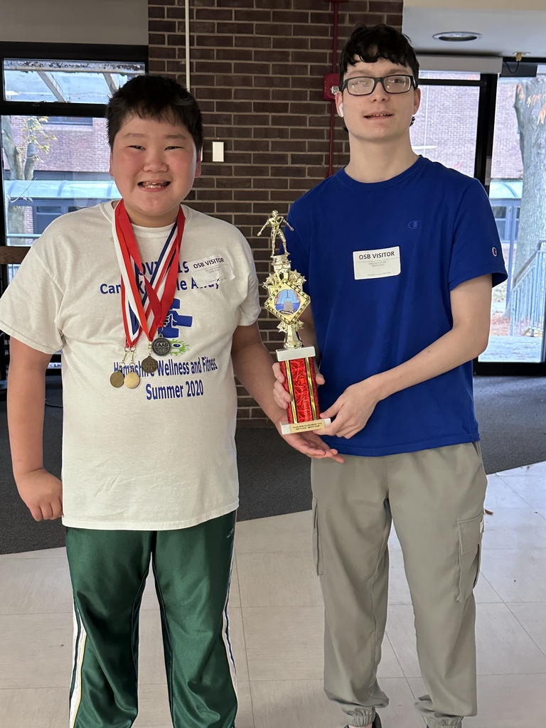 Two male student-athletes pose with a red and gold-colored trophy.