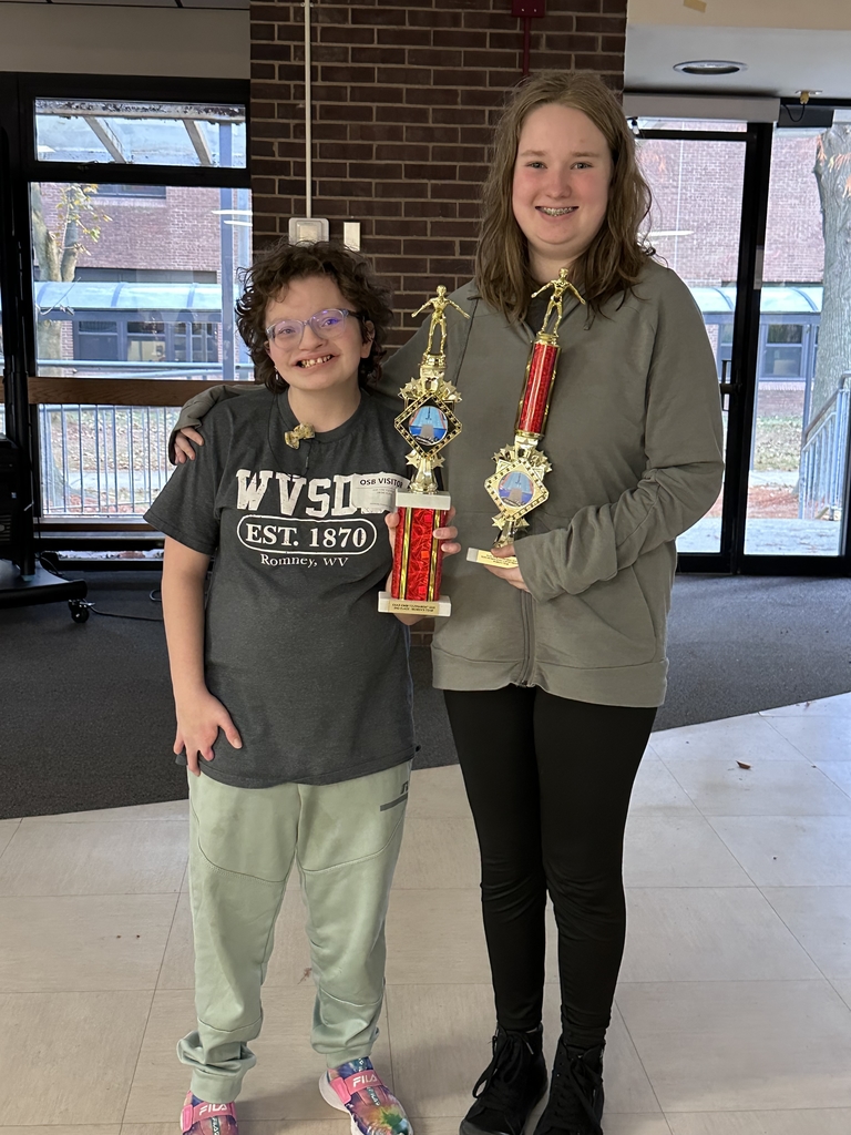 Two female student-athletes each posing with a red and gold-colored trophy.