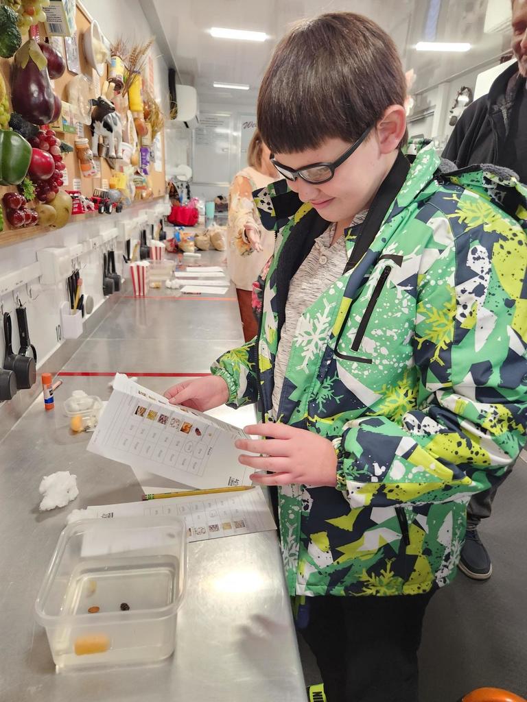 A male student with dark hair and glasses looks down as he tests his hypothesis with popcorn.