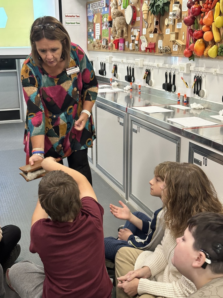 A female representative hands an object to a male student.