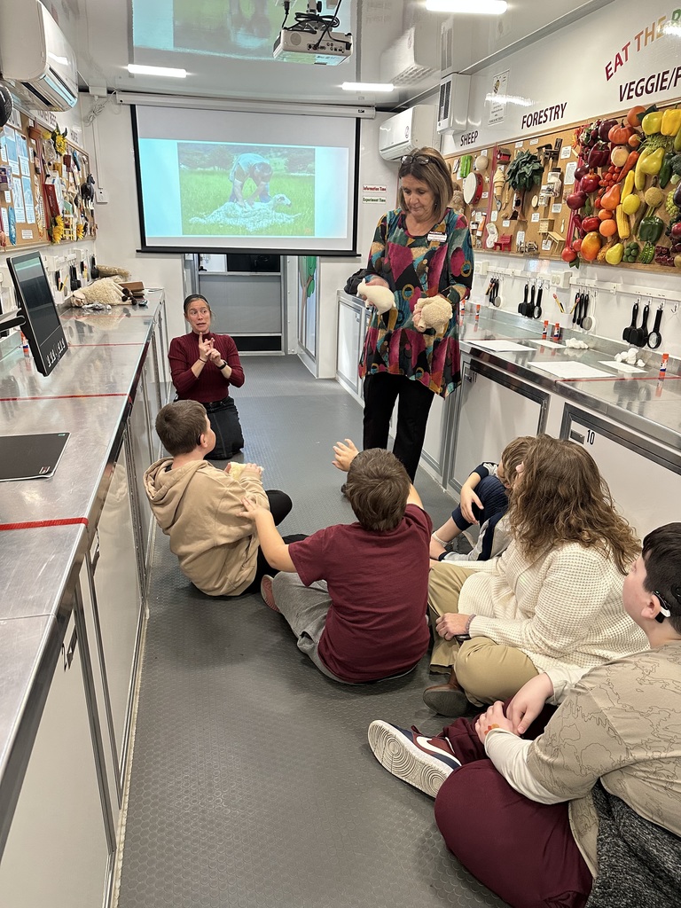 A female representative holds up two examples of livestock animals.