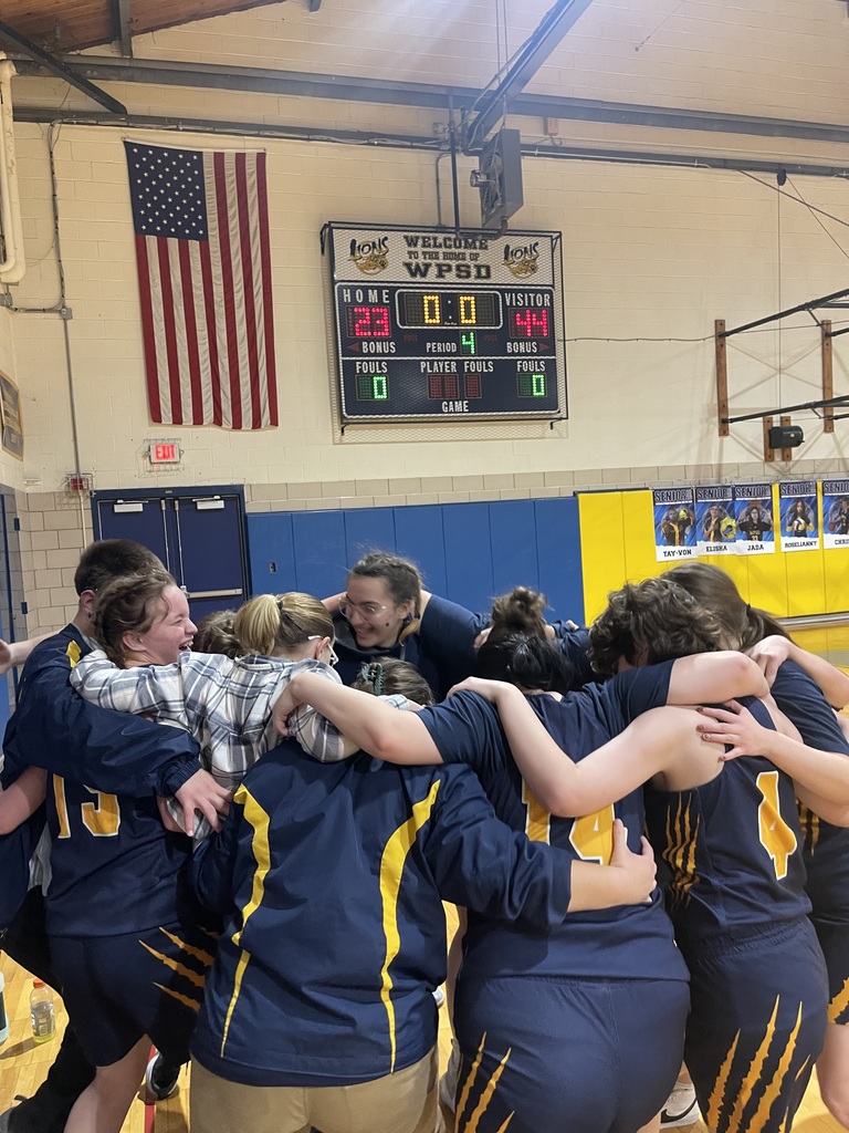 Girls basketball players are huddled together with their arms around each other's shoulders.