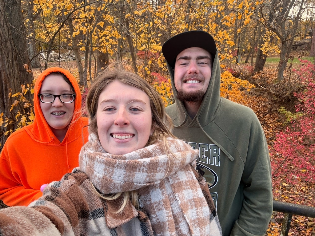 Ms. Franki Harrah, CAP Specialist takes a selfie with two students. Behind them, the trees are turning shades of orange, red, and yellow.
