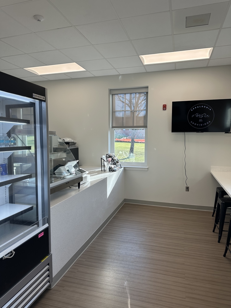 An overview of the Appalachia Provisions Cafe with a refrigerator, eating area, and stools.