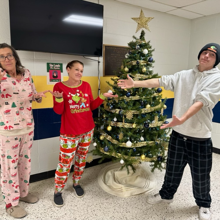Two female staff members dressed in holiday pajamas look innocent as a male student points their way looking disappointed. 