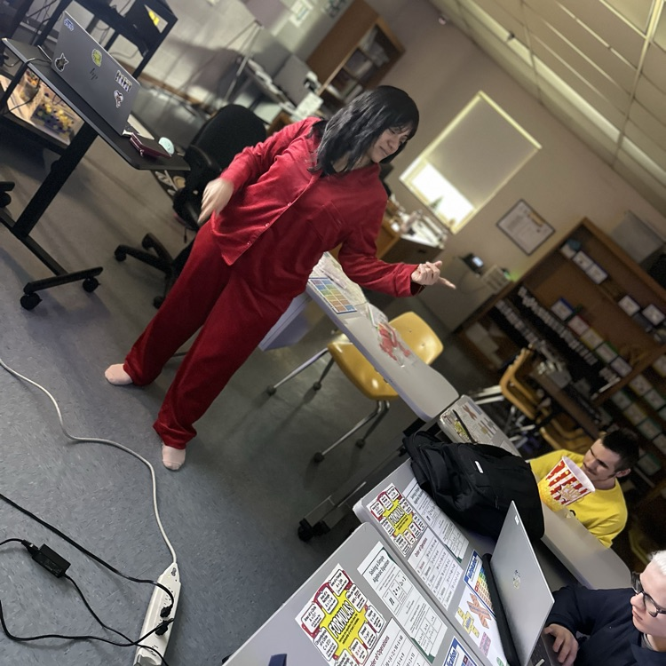A female teacher is wearing a matching red pajama set is in front of the class teaching.