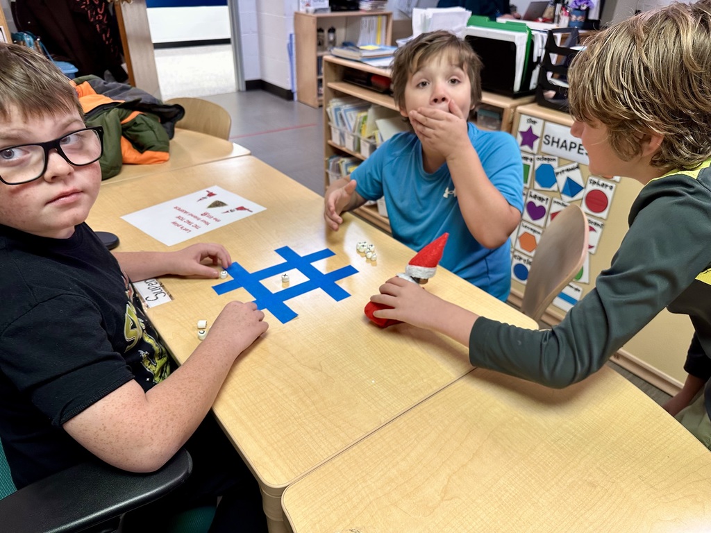 A male student touches the elf while another student gasps with his hand over his mouth in disbelief. 
