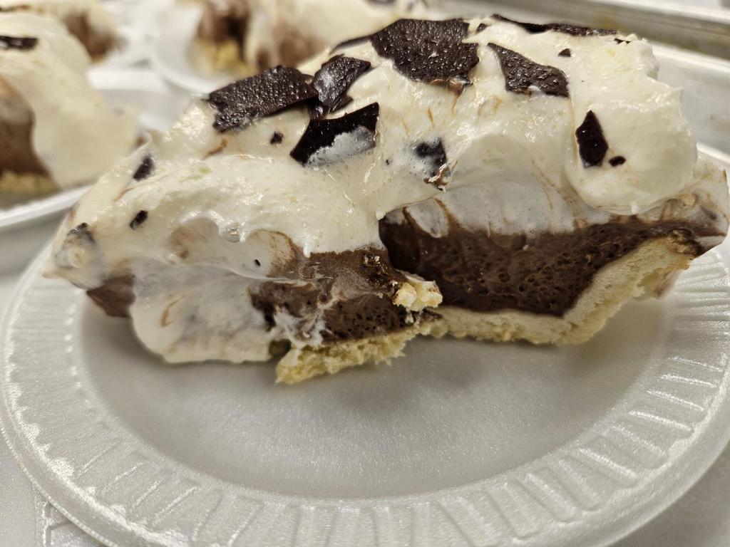 Up-close photo of a piece of chocolate pie on a white-colored paper plate. 